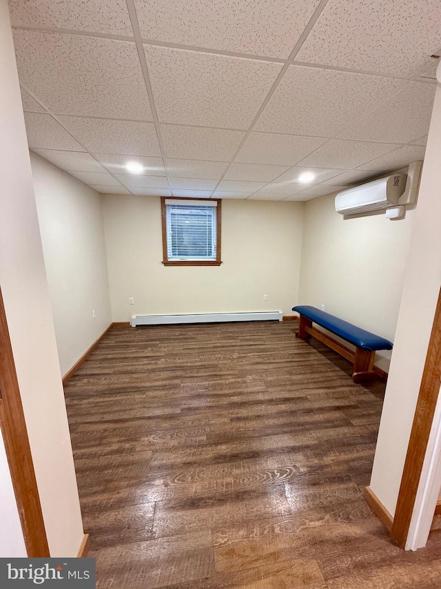 11003 Marty St NW, Lavale, MD 21502 - finished below grade area featuring an AC wall unit, a baseboard heating unit, wood finished floors, baseboards, and a drop ceiling