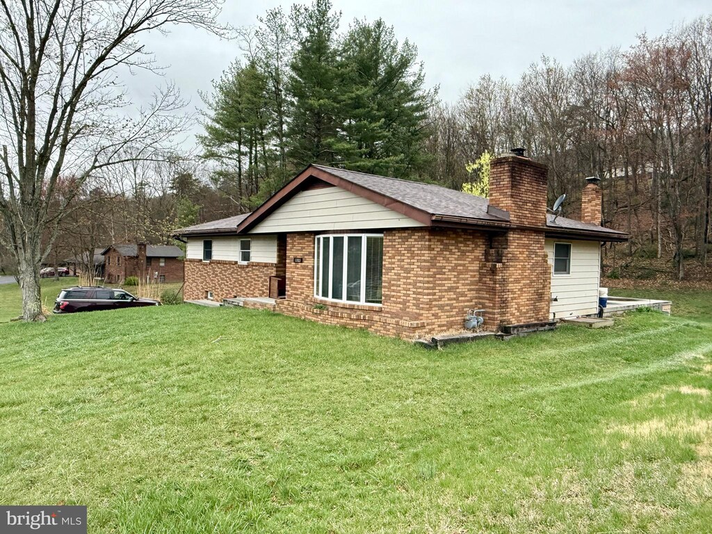view of side of home featuring a lawn, a chimney, and brick siding