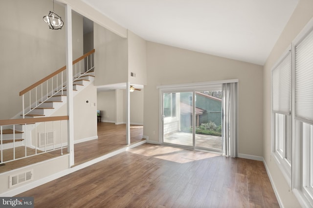 interior space featuring stairway, wood finished floors, visible vents, and high vaulted ceiling