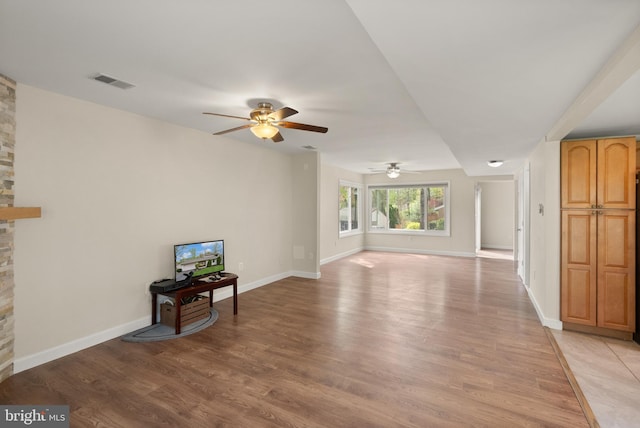 unfurnished living room with light wood finished floors, baseboards, a ceiling fan, and visible vents
