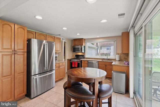 kitchen with a sink, tasteful backsplash, visible vents, appliances with stainless steel finishes, and light tile patterned floors