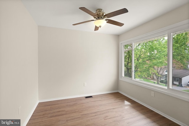 empty room featuring visible vents, light wood finished floors, baseboards, and a ceiling fan