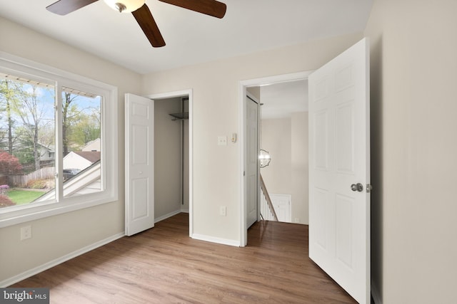 unfurnished bedroom with light wood finished floors, baseboards, and a ceiling fan
