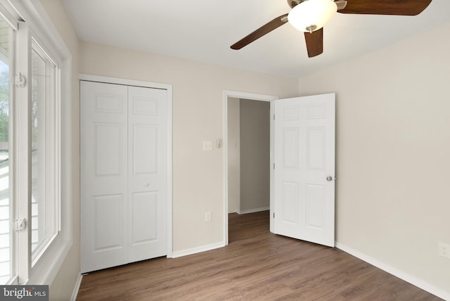 unfurnished bedroom with baseboards, wood finished floors, and multiple windows