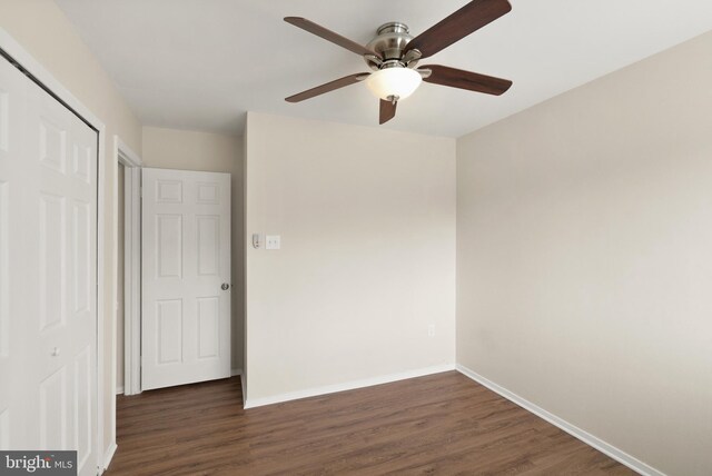 unfurnished bedroom with a closet, a ceiling fan, baseboards, and dark wood-style floors