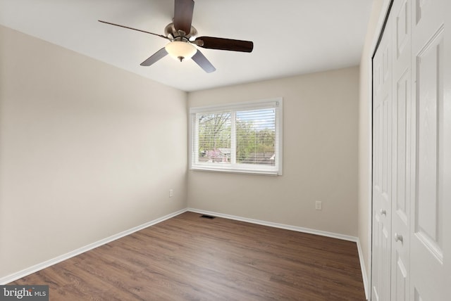 unfurnished bedroom featuring wood finished floors, a closet, baseboards, and visible vents