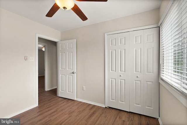 unfurnished bedroom with baseboards, wood finished floors, multiple windows, and a closet