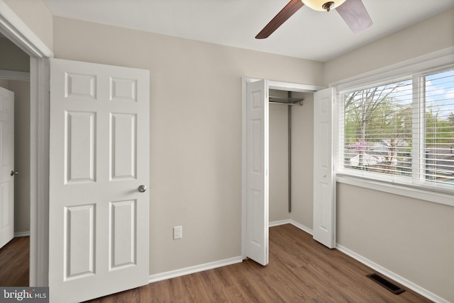 unfurnished bedroom featuring baseboards, wood finished floors, visible vents, and a closet