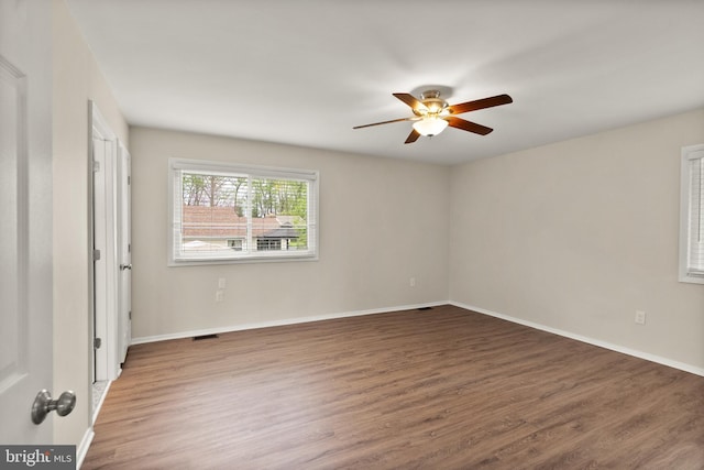 empty room featuring baseboards, a ceiling fan, wood finished floors, and visible vents