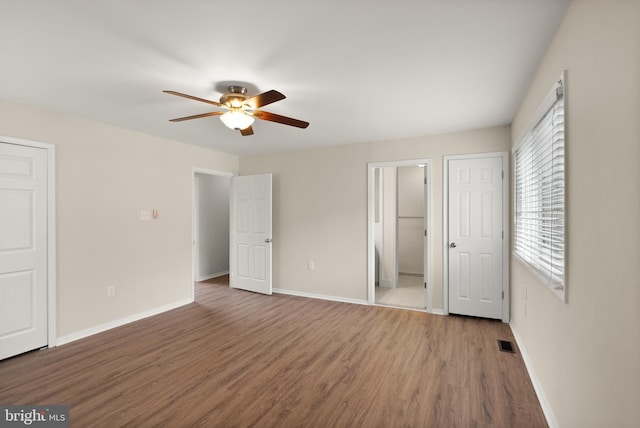 unfurnished bedroom featuring wood finished floors, visible vents, a ceiling fan, and baseboards