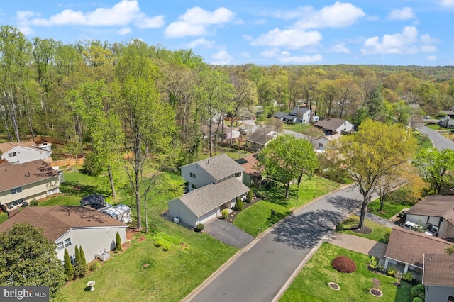 drone / aerial view featuring a wooded view and a residential view