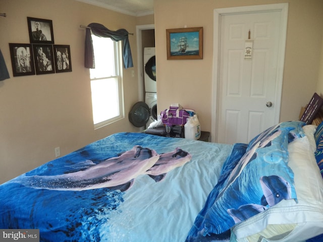 bedroom featuring stacked washer and dryer and crown molding