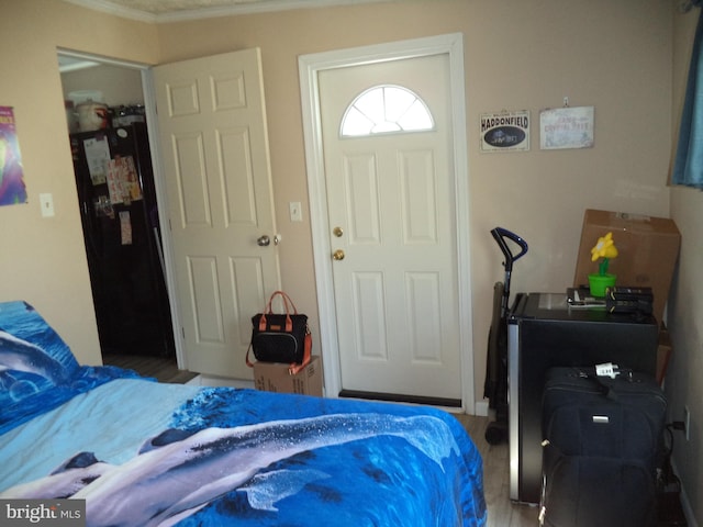bedroom featuring crown molding, freestanding refrigerator, and wood finished floors