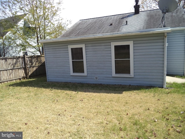 rear view of property with a yard, fence, and roof with shingles