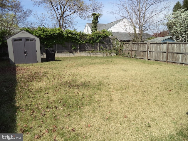 view of yard with a storage shed, an outbuilding, and a fenced backyard