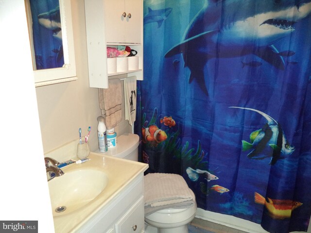 full bath featuring toilet, curtained shower, and vanity