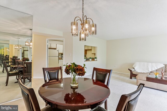 dining room featuring baseboards, a notable chandelier, and light carpet