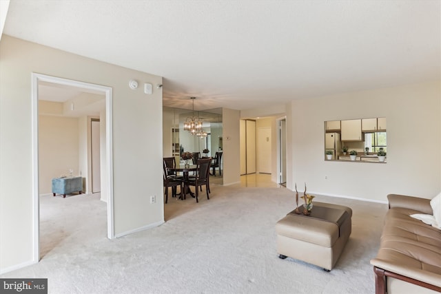 living room with a chandelier, baseboards, and light carpet
