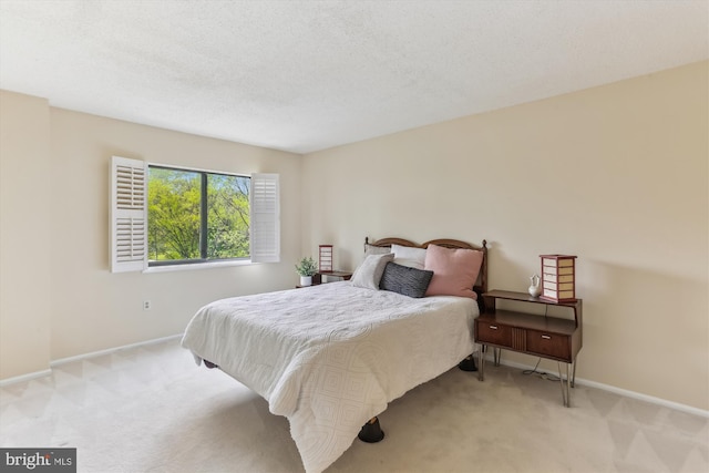 bedroom with baseboards, light carpet, and a textured ceiling