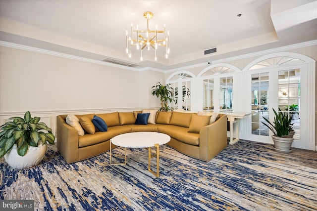 carpeted living room with an inviting chandelier, a raised ceiling, visible vents, and wainscoting