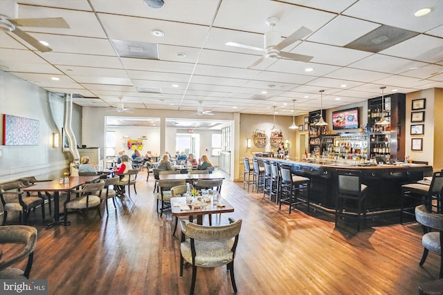 interior space with ceiling fan, wood finished floors, and a dry bar
