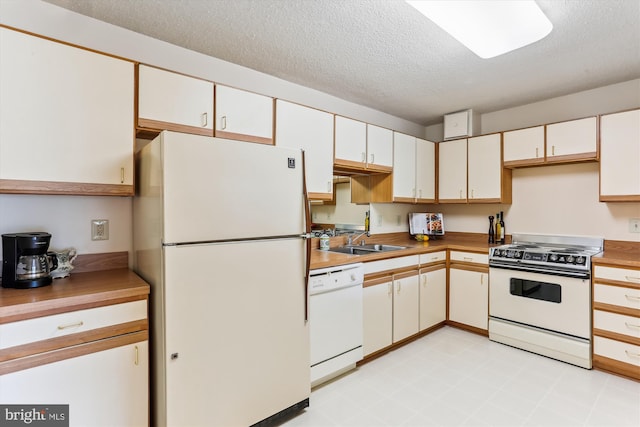 kitchen with light floors, white appliances, a sink, white cabinetry, and a textured ceiling