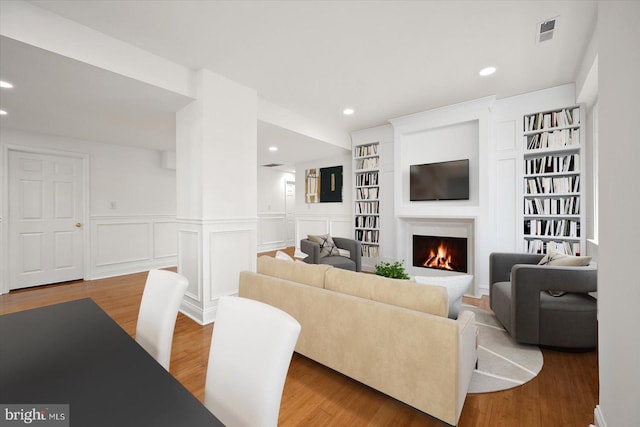 1506 N Bay Shore Dr, Milton, DE 19968 - living area featuring light wood-style floors, a decorative wall, visible vents, and a lit fireplace