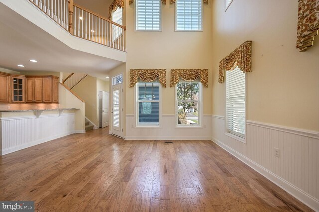 105 Arch St, Milton, DE 19968 - unfurnished living room featuring recessed lighting, stairway, a wainscoted wall, a high ceiling, and wood-type flooring