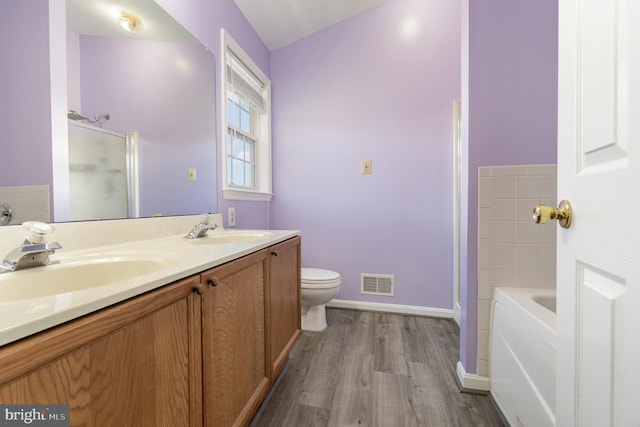 full bath featuring visible vents, a sink, a bath, and wood finished floors