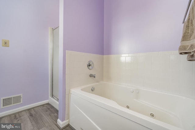 full bath featuring a jetted tub, visible vents, a shower stall, wood finished floors, and baseboards