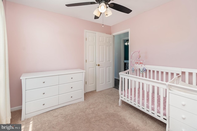 carpeted bedroom with a nursery area and ceiling fan