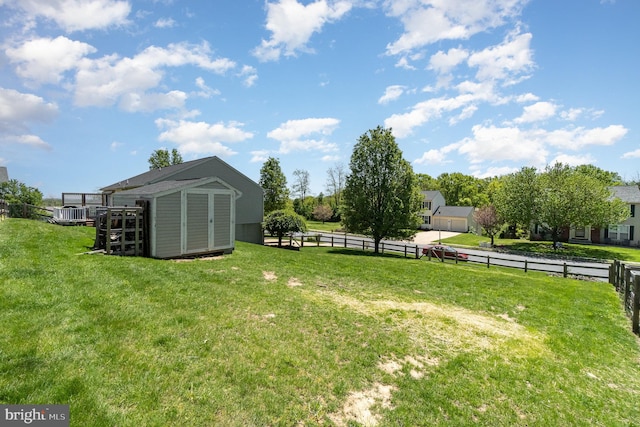 view of yard featuring a storage unit, an outdoor structure, and fence