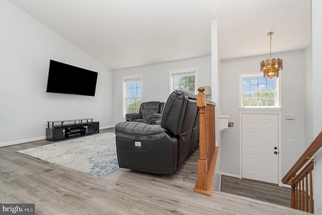 living room featuring baseboards, lofted ceiling, wood finished floors, and a chandelier