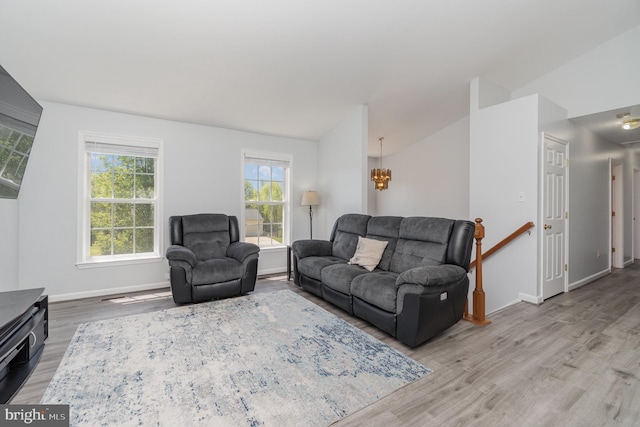 living room featuring baseboards, a chandelier, wood finished floors, and lofted ceiling