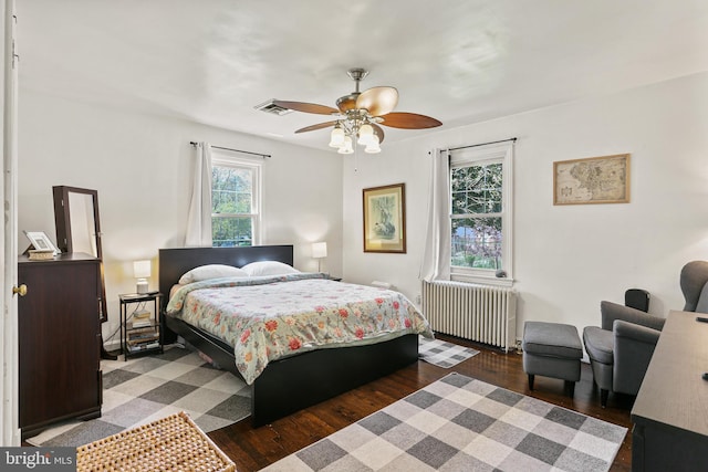 bedroom with radiator, wood finished floors, visible vents, and a ceiling fan