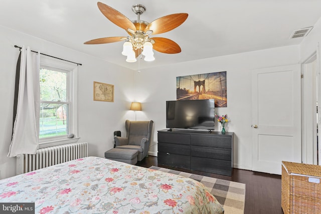 bedroom featuring radiator heating unit, wood finished floors, visible vents, and ceiling fan