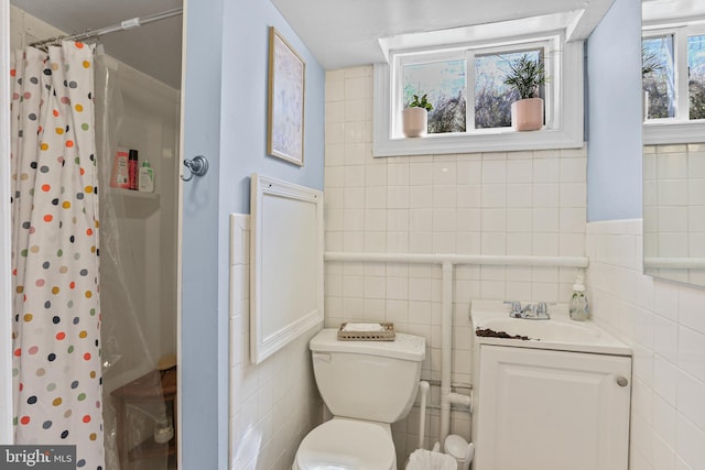 bathroom featuring tile walls, vanity, curtained shower, and toilet