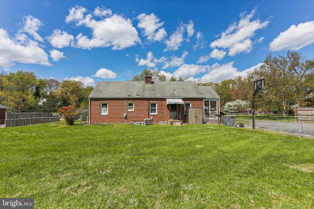 back of property with a lawn, a chimney, and a fenced backyard