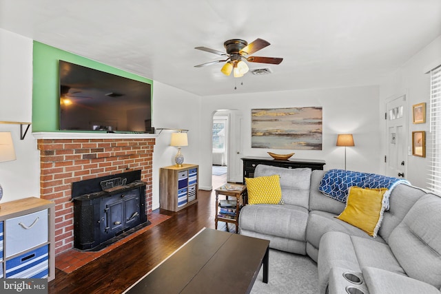 living area featuring ceiling fan, arched walkways, wood finished floors, and visible vents