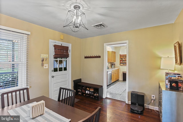 dining room featuring a chandelier, wood finished floors, visible vents, and baseboards