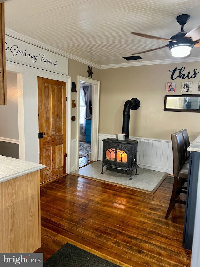 1671 Fravel Rd, Woodstock, VA 22664 - living area featuring ornamental molding, dark wood-style floors, a wainscoted wall, a wood stove, and ceiling fan