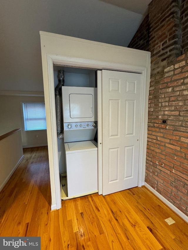1637 Fleet St, Baltimore, MD 21231 - laundry area featuring laundry area, stacked washer / dryer, wood finished floors, brick wall, and baseboards