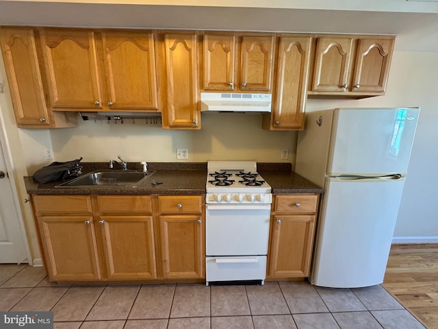 1637 Fleet St, Baltimore, MD 21231 - kitchen featuring white appliances, brown cabinetry, under cabinet range hood, light tile patterned flooring, and a sink