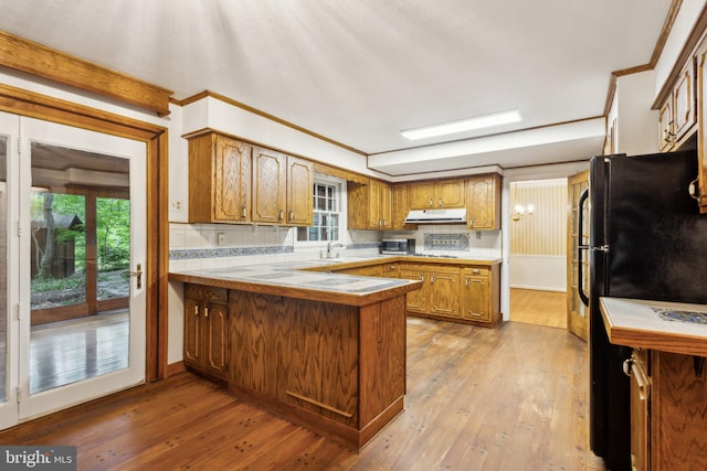 5936 River Dr, Lorton, VA 22079 - kitchen featuring under cabinet range hood, a peninsula, brown cabinetry, crown molding, and light wood-type flooring