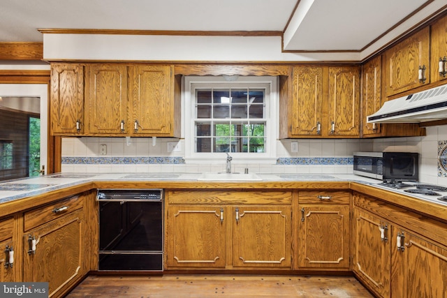 5936 River Dr, Lorton, VA 22079 - kitchen featuring black dishwasher, under cabinet range hood, a sink, brown cabinets, and ornamental molding