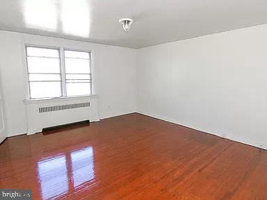 6846 Radbourne Rd, Upper Darby, PA 19082 - empty room featuring wood finished floors and radiator heating unit