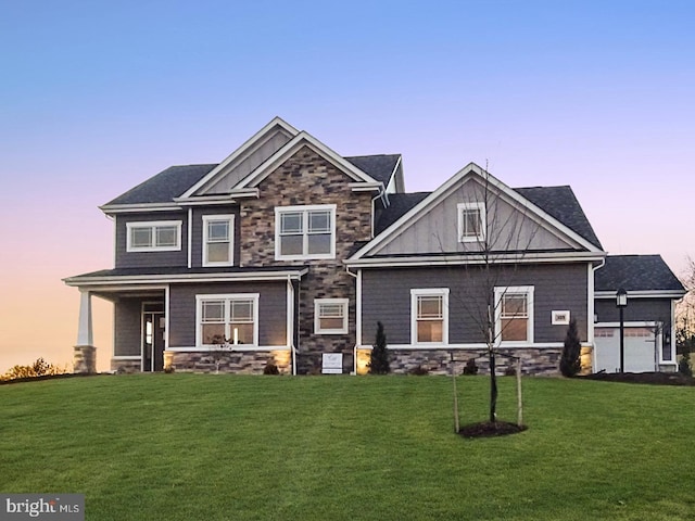 craftsman house featuring covered porch, stone siding, a front yard, and board and batten siding