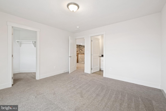 unfurnished bedroom featuring baseboards, a spacious closet, a closet, and carpet floors