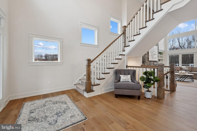 interior space with baseboards, stairway, a high ceiling, and wood finished floors