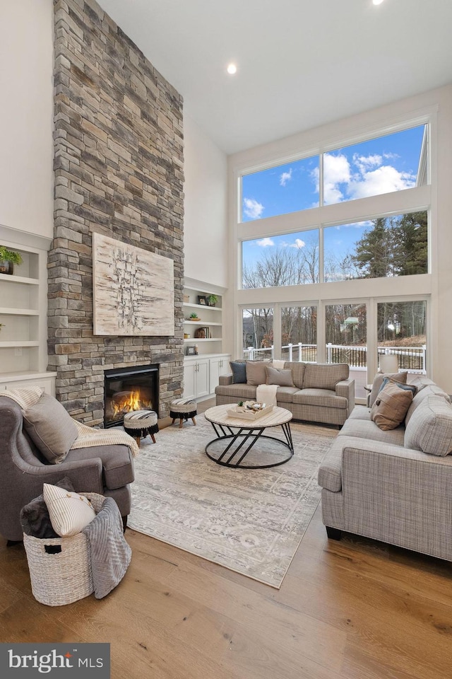 living room featuring plenty of natural light, a fireplace, wood finished floors, and a high ceiling